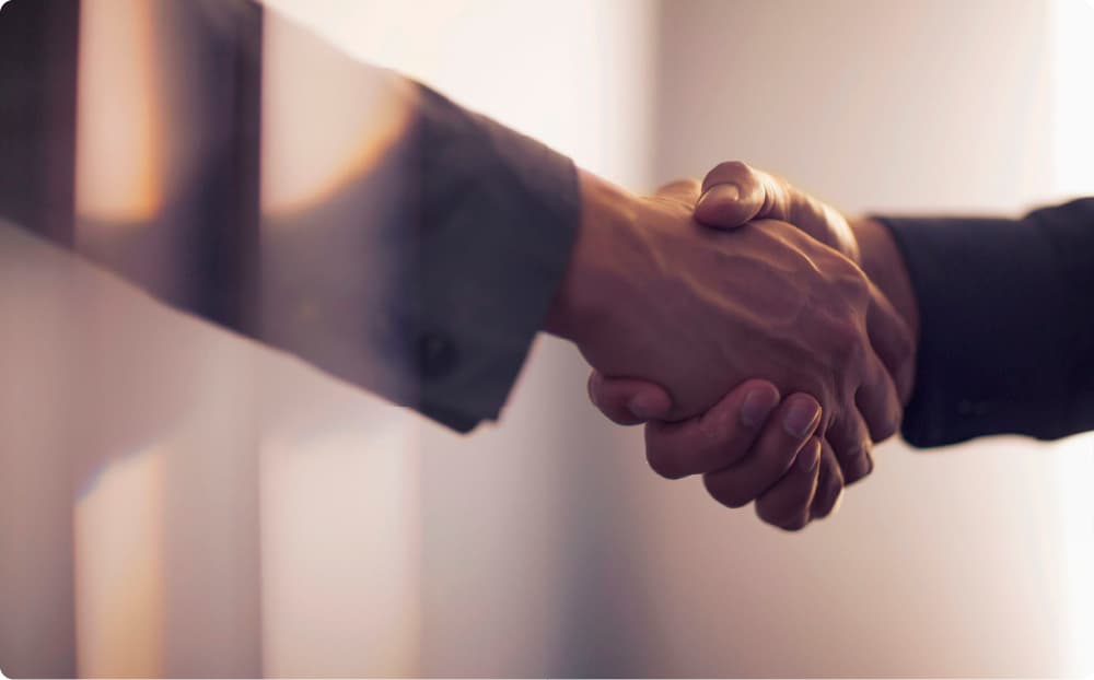 スーツ姿の男性同士の、握手する手にフォーカスしたイメージ。