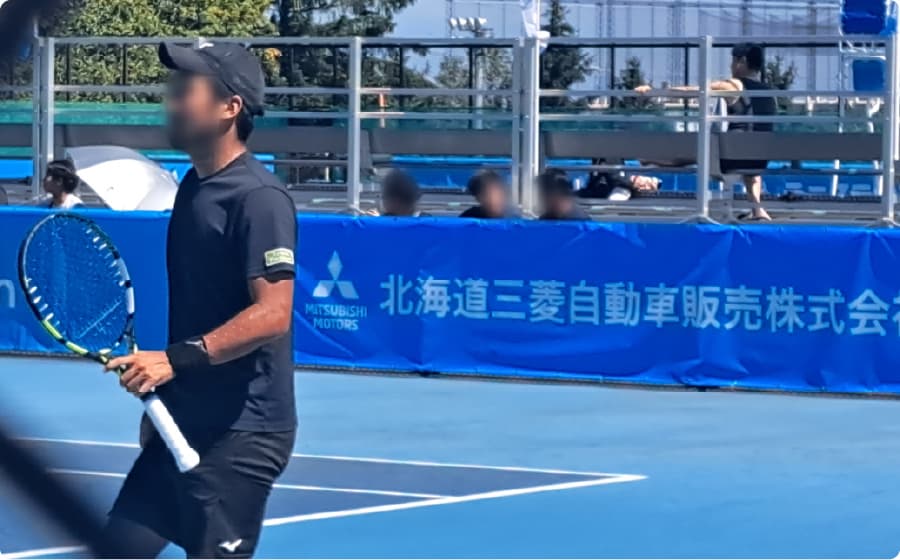 テニス大会に出場している、黒いウェアを着た選手の写真